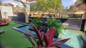 A rooftop pool with artificial grass, surrounded by potted plants and a statue. - Hotel Sriram JB Residency (Virudhunagar)