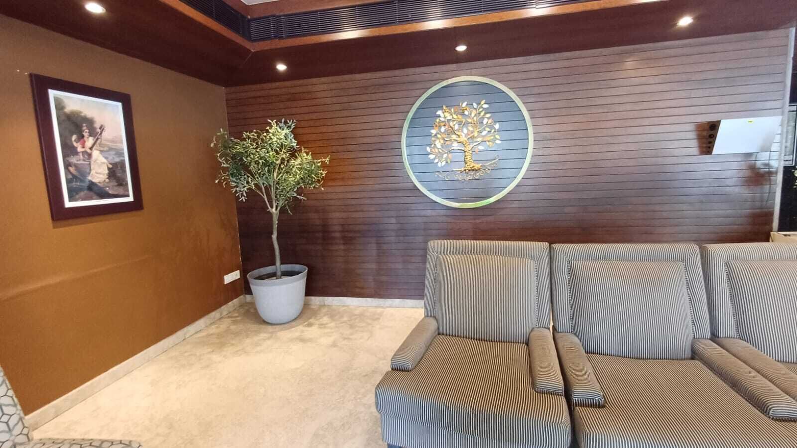 A modern living room with a sofa set, a potted plant, and a decorative wall piece.