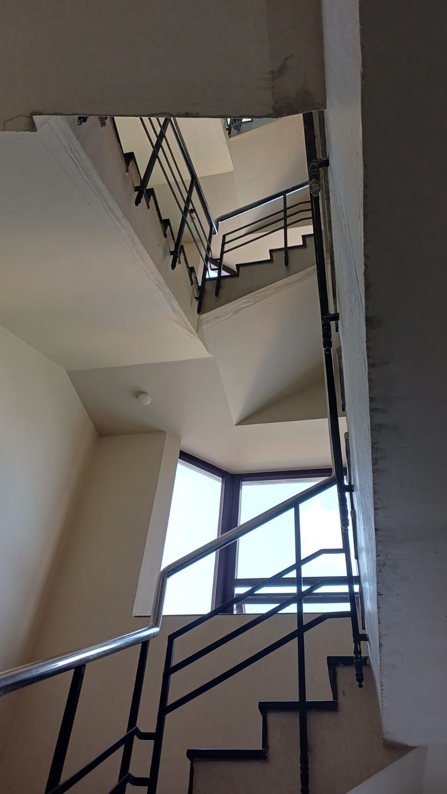Un interno su più livelli con una scala, una finestra e una luce a soffitto.