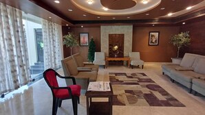 A lobby with a sofa, chairs, a coffee table, and a fireplace. - Hotel Sriram JB Residency (Virudhunagar)