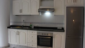 Eine Küche mit weißen Schränken, einem Edelstahl-Kühlschrank und einem eingebauten Backofen.