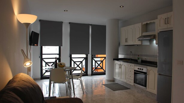 Eine moderne Küche mit weißen Schränken, einem Edelstahlkühlschrank und einem Essbereich mit Tisch und Stühlen.