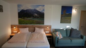 A hotel room with two beds, a sofa, and two paintings on the walls. - Ferienhaus Mott (Lermoos)