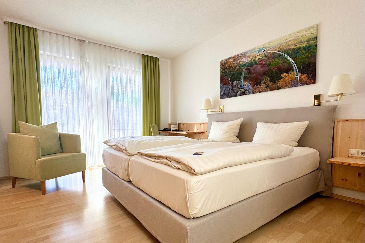 Een hotelkamer met een groot bed, een stoel, een bureau en een schilderij aan de muur.