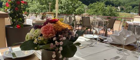 An outdoor dining area with a table set for two, complete with cutlery and a glass of water.