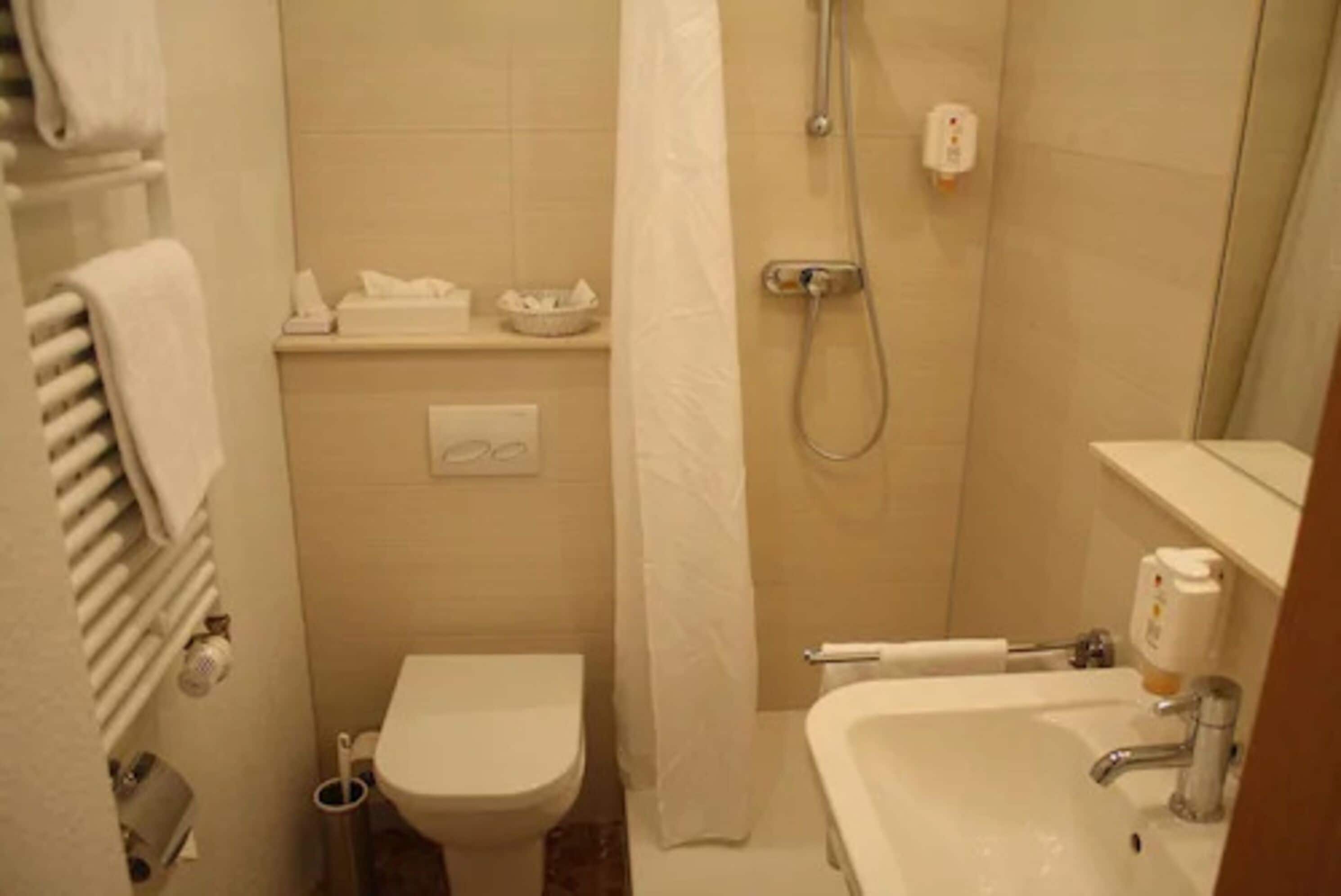 A small bathroom with a toilet, a sink, a shower, and a towel rack.