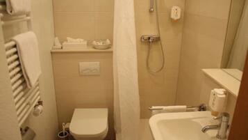 A small bathroom with a toilet, a sink, a shower, and a towel rack.