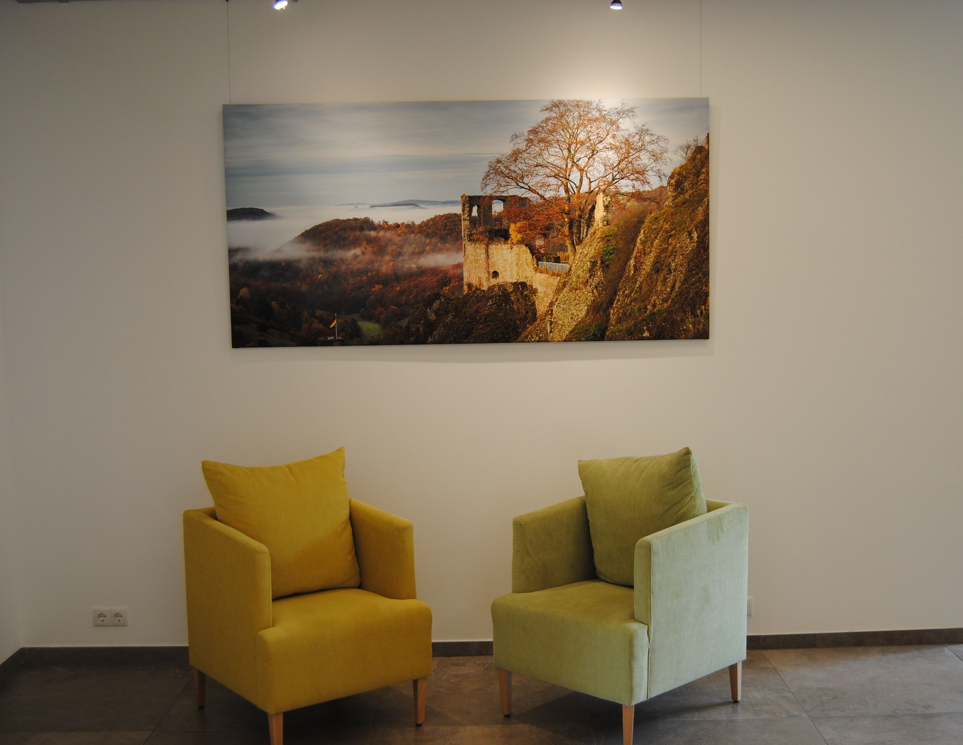 A room with two armchairs and a large landscape painting on the wall.