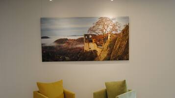 A room with two armchairs and a large landscape painting on the wall.