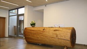 En receptionsdisk gjord av en stor trädstam, en krukväxt och en glasdörr som leder ut.