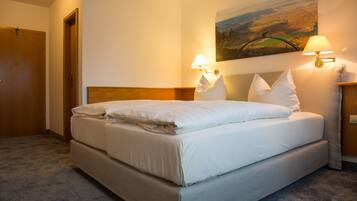 A neatly made bed with white linens, a headboard, and two wall-mounted lamps on either side.