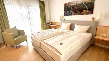 Habitación de hotel con cama doble, una silla, un escritorio y un cuadro en la pared.