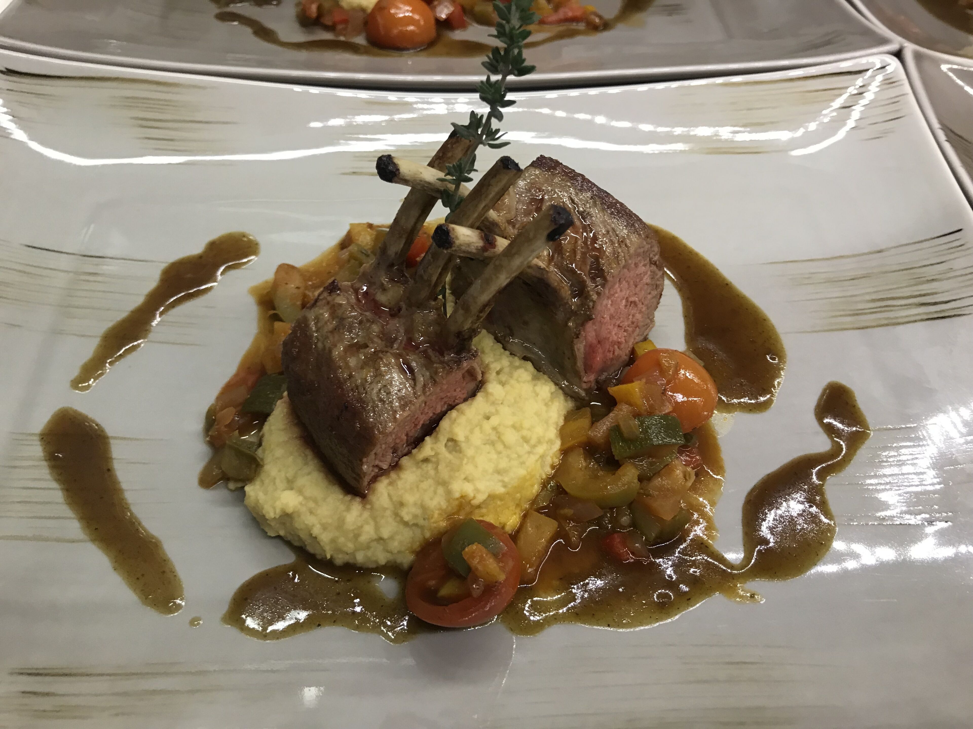 A plated dish with two pieces of meat, mashed potatoes, and vegetables.