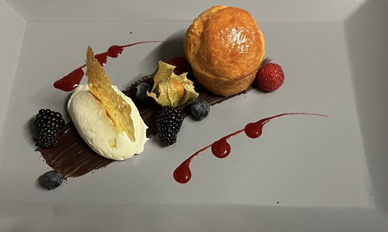Een nagerechtenbord met patisserie, ijs, bessen en chocoladesaus.