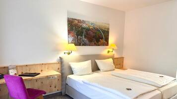Une chambre d’hôtel avec un lit, un bureau, une chaise et un tableau au mur.