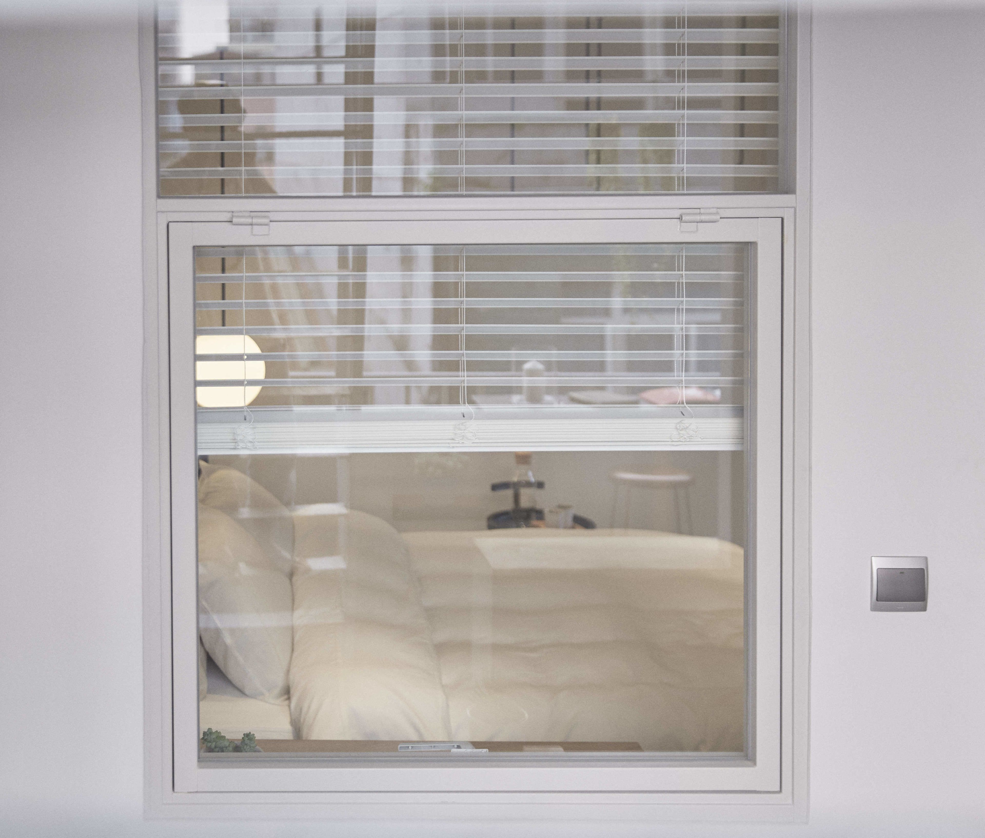 A room with a bed, a nightstand, and a window with blinds.