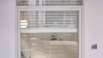 A room with a bed, a nightstand, and a window with blinds.