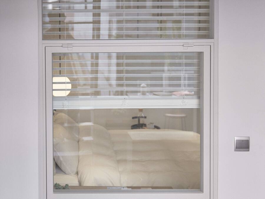 A room with a bed, a nightstand, and a window with blinds.