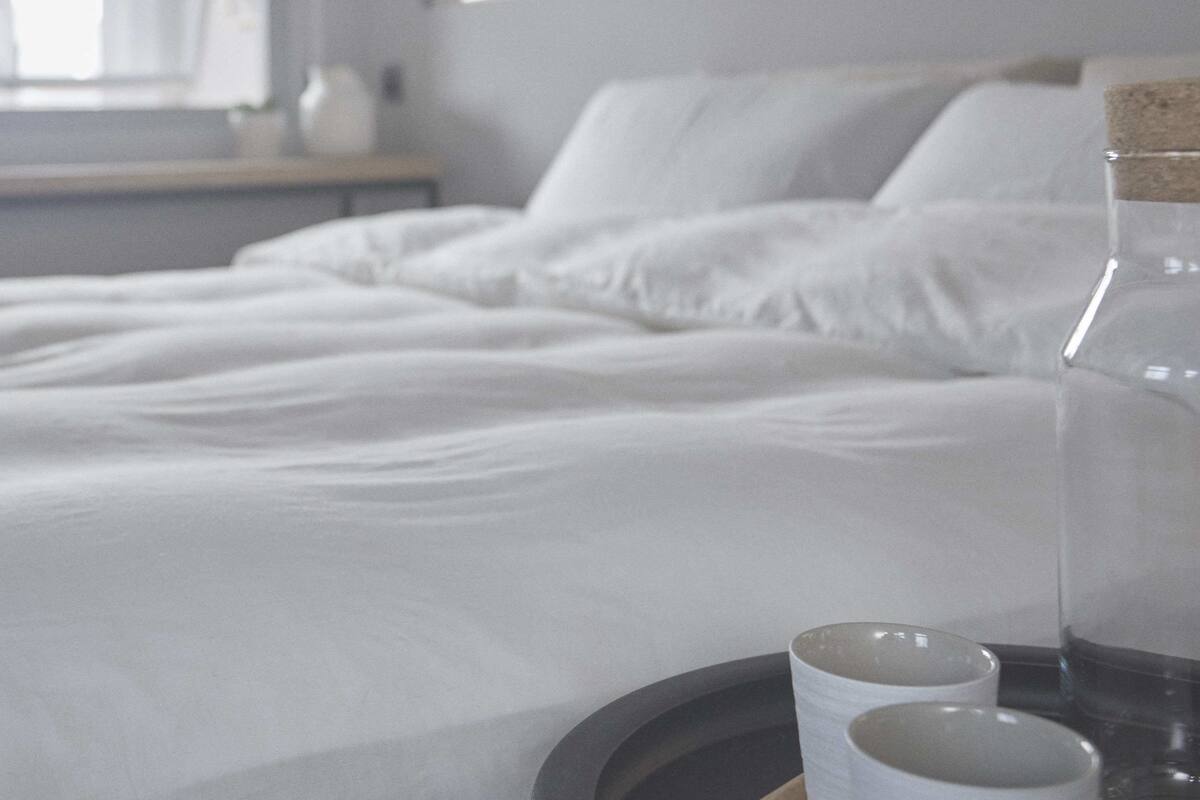 A neatly made bed with white linens in a hotel room.