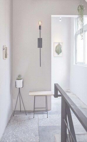 A modern interior with a minimalist design, featuring a bench, a wall-mounted light, and a hanging plant. - The Door Inn (Taipei)