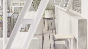Een modern balkon buiten met een metalen trap, een kleine tafel en een bloempot.