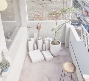 A balcony with a potted plant, a bird sculpture, and white blocks arranged in a pattern. - The Door Inn (Taipei)