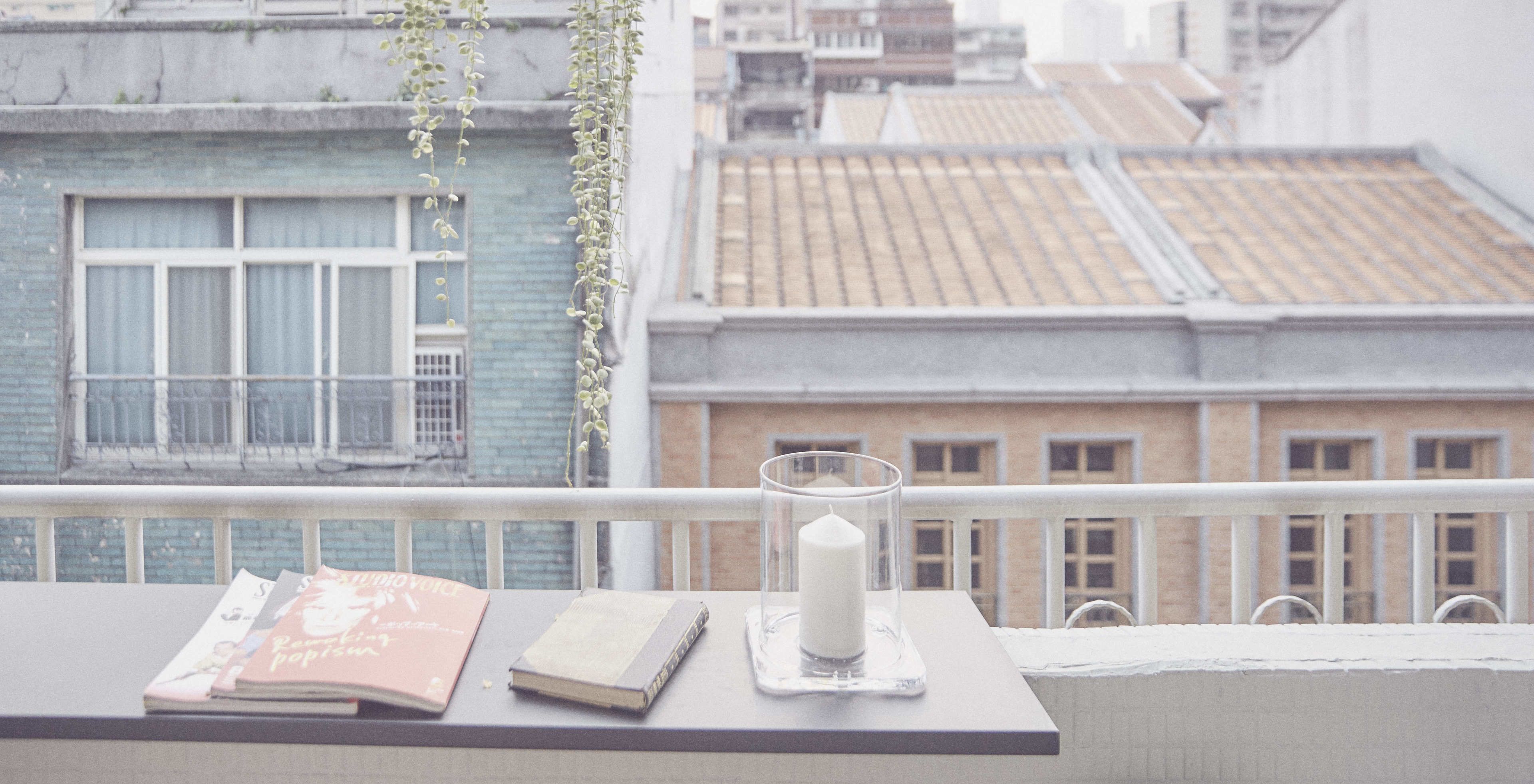 A balcony with a table holding books and a candle holder.