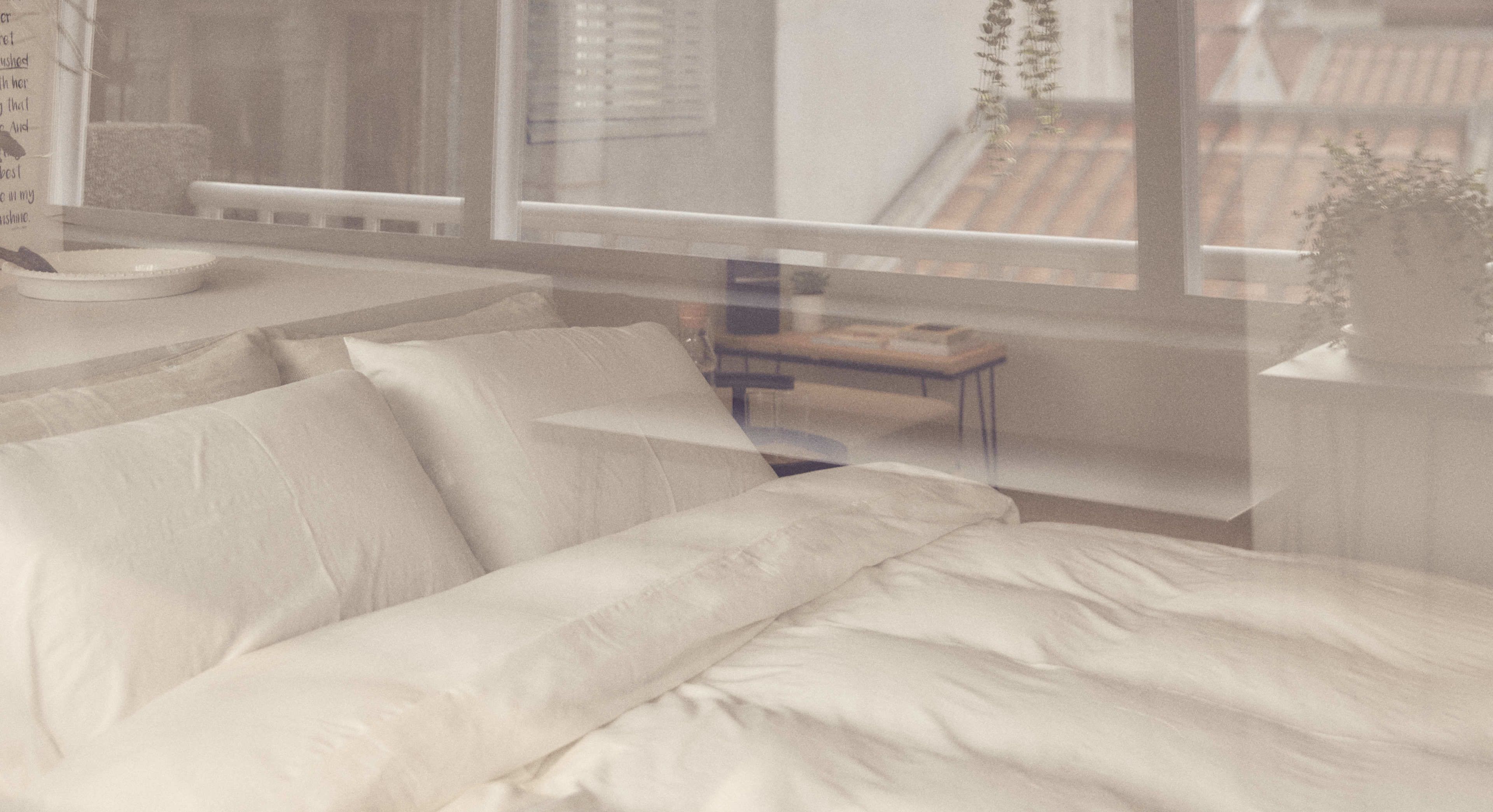 A bedroom with a bed, a bedside table, and a window.