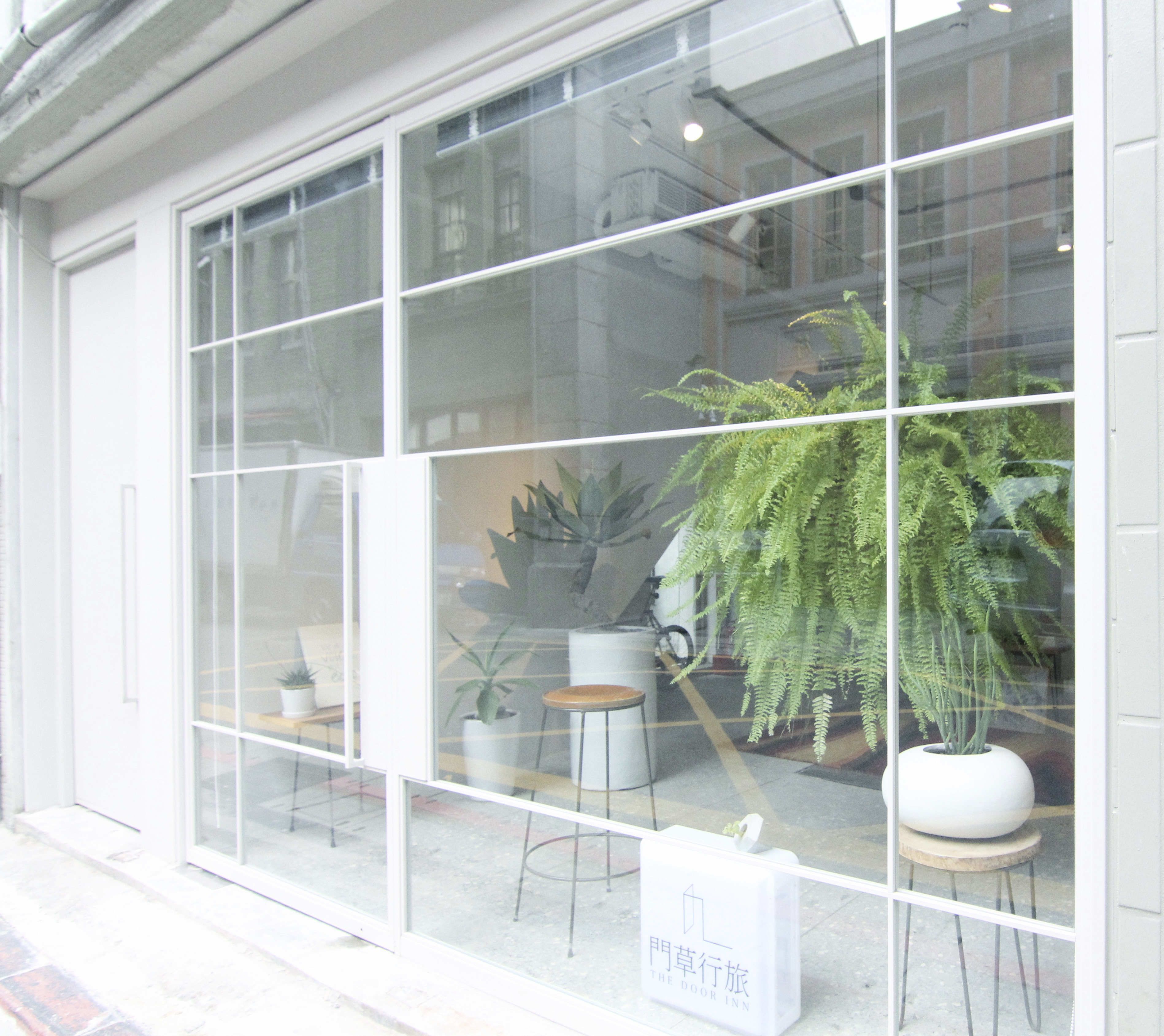 A hotel entrance with large windows, potted plants, and a sign for 'The Door Inn'.