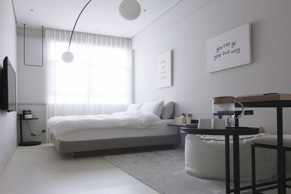 A modern hotel room with a large bed, bedside tables, a small round table, and a wall-mounted TV.