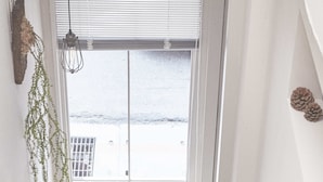 Een trap die leidt naar een balkon met een potplant, een hangplant en een kleine houten stoel.