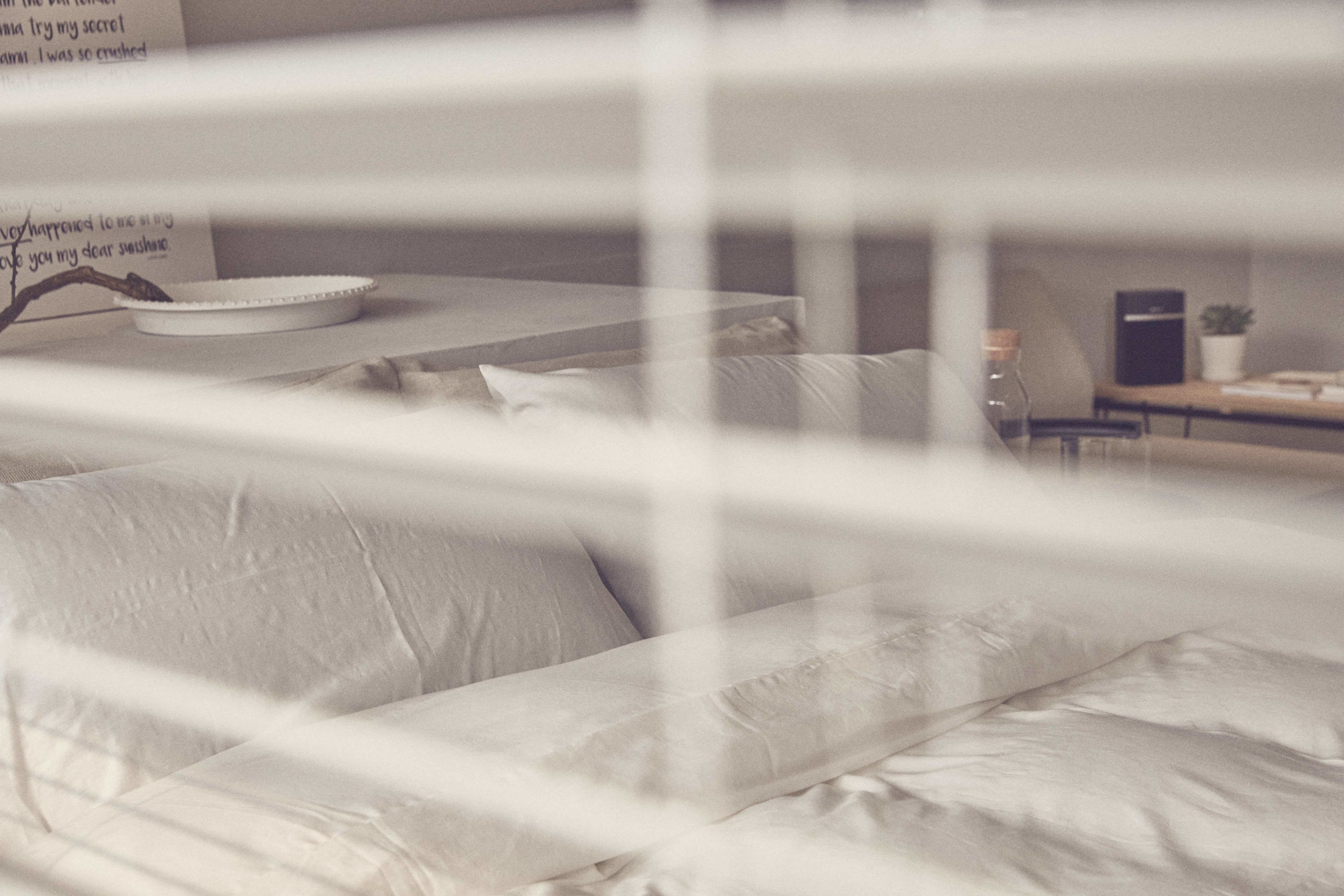 A bed with white bedding and a bedside table with a lamp.