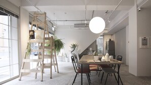 Een moderne eethoek met een houten ladder, potplanten en een grote ronde lamp.