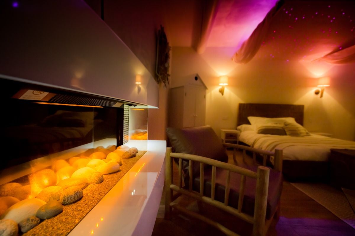 Un dormitorio moderno con cama, mesita de noche y una pequeña mesa con lámpara.