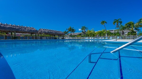 Swimmers can enjoy a well-maintained pool with lane markings, surrounded by a fence and shaded areas.
