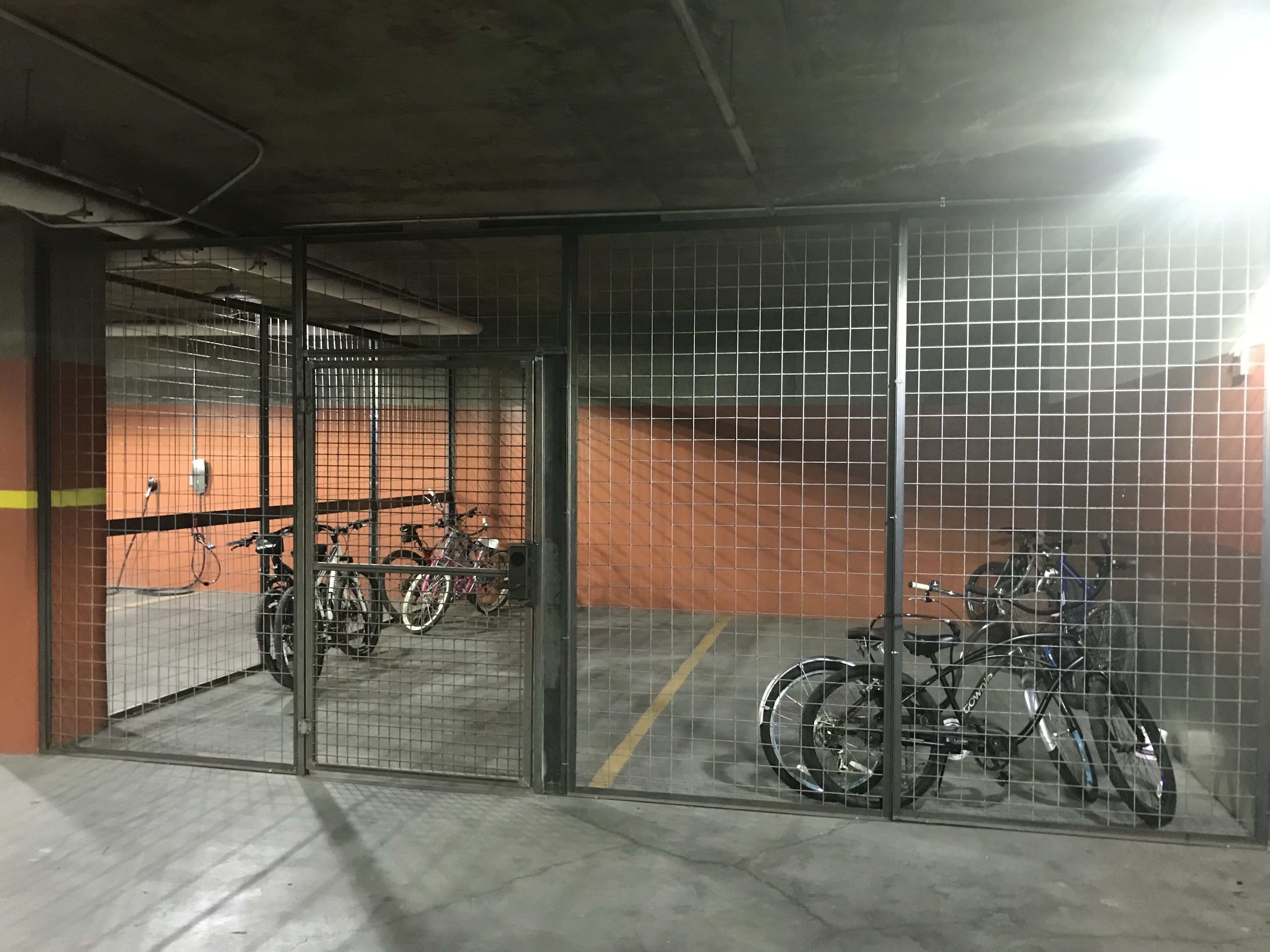 A parking garage with metal fencing and bicycles parked inside.