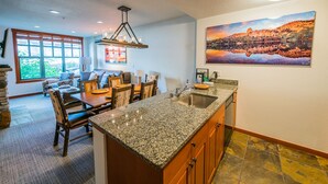 A kitchen with granite countertops, wooden cabinets, and a large window. - Modern Condo in Heart of Village, 1st floor, Steps to Gondola & all Amenities   (Mammoth Lakes)