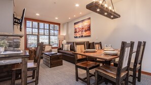 A dining area with a wooden table, chairs, and a sofa. - Modern Condo in Heart of Village, 1st floor, Steps to Gondola & all Amenities   (Mammoth Lakes)