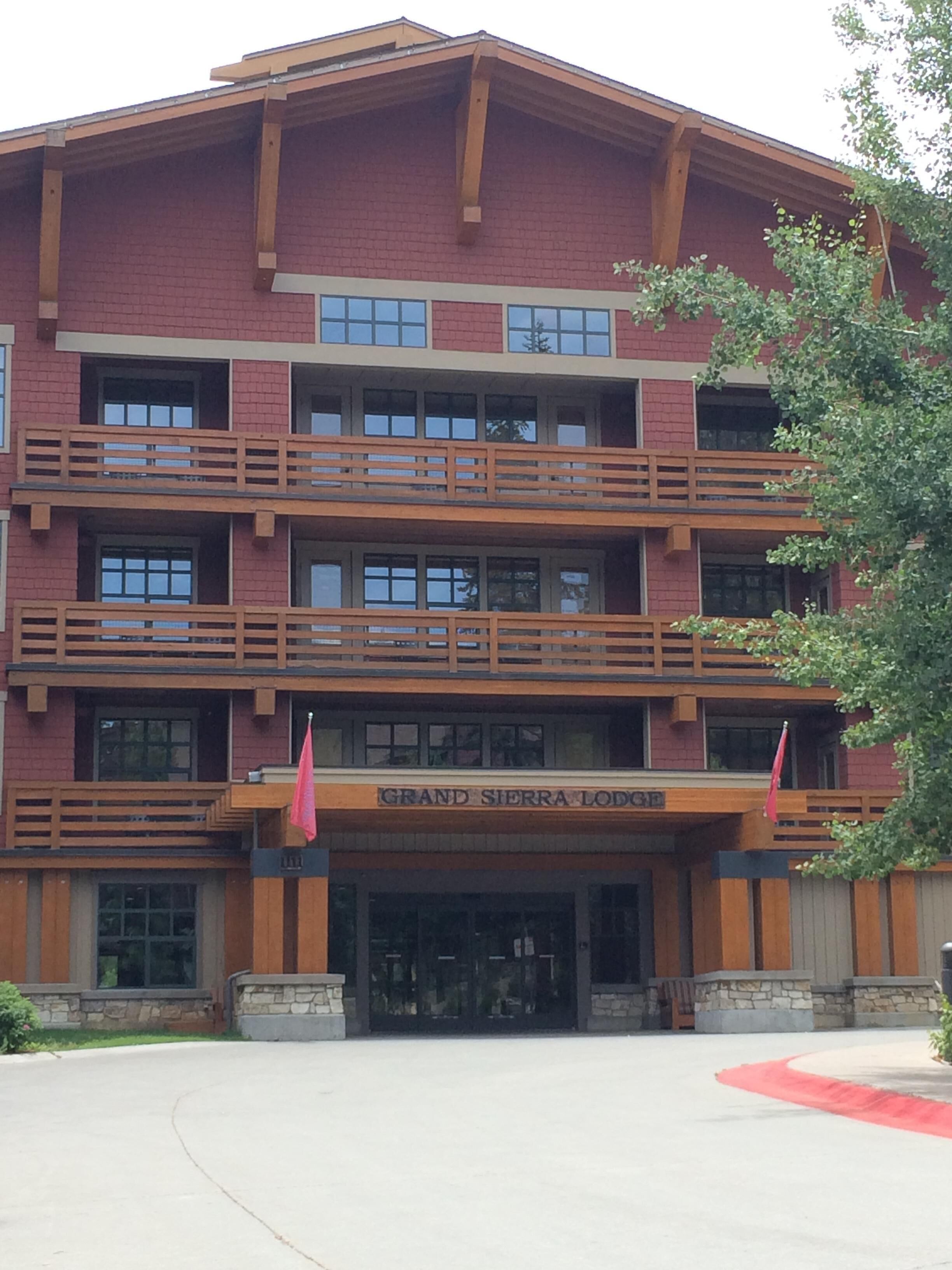 A multi-story building with a red brick facade, balconies, and a sign reading "Grand Sierra Lodge".