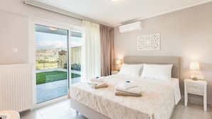 Une chambre d’hôtel avec un grand lit, une porte-fenêtre coulissante donnant sur un balcon, un radiateur blanc et une table de chevet avec une lampe.