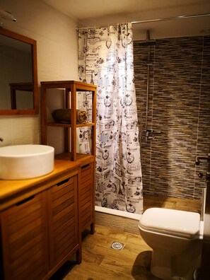 A bathroom with a wooden vanity, a white sink, a mirror, a shower curtain with Parisian text, and a tiled shower enclosure. - Effrosini Stonehouse Portaria (Volos)