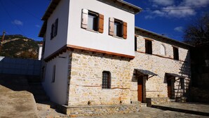 Un edificio in pietra di due piani con facciata bianca e persiane in legno, con una scala in pietra che conduce all'ingresso.