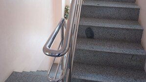 Una escalera con barandas de metal y piso alfombrado.