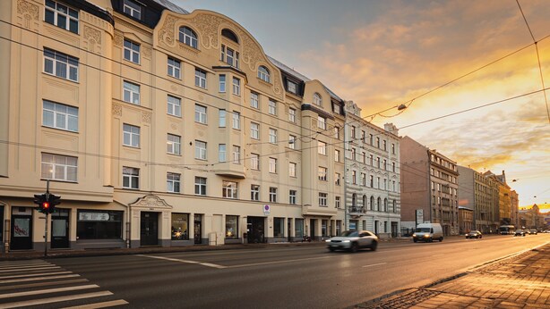 Un edificio de varios pisos con un estilo arquitectónico clásico, que presenta amplios ventanales y detalles decorativos.