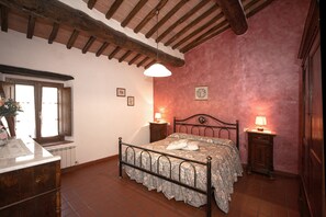 Une chambre à coucher avec un lit, des tables de chevet, une fenêtre et un radiateur.