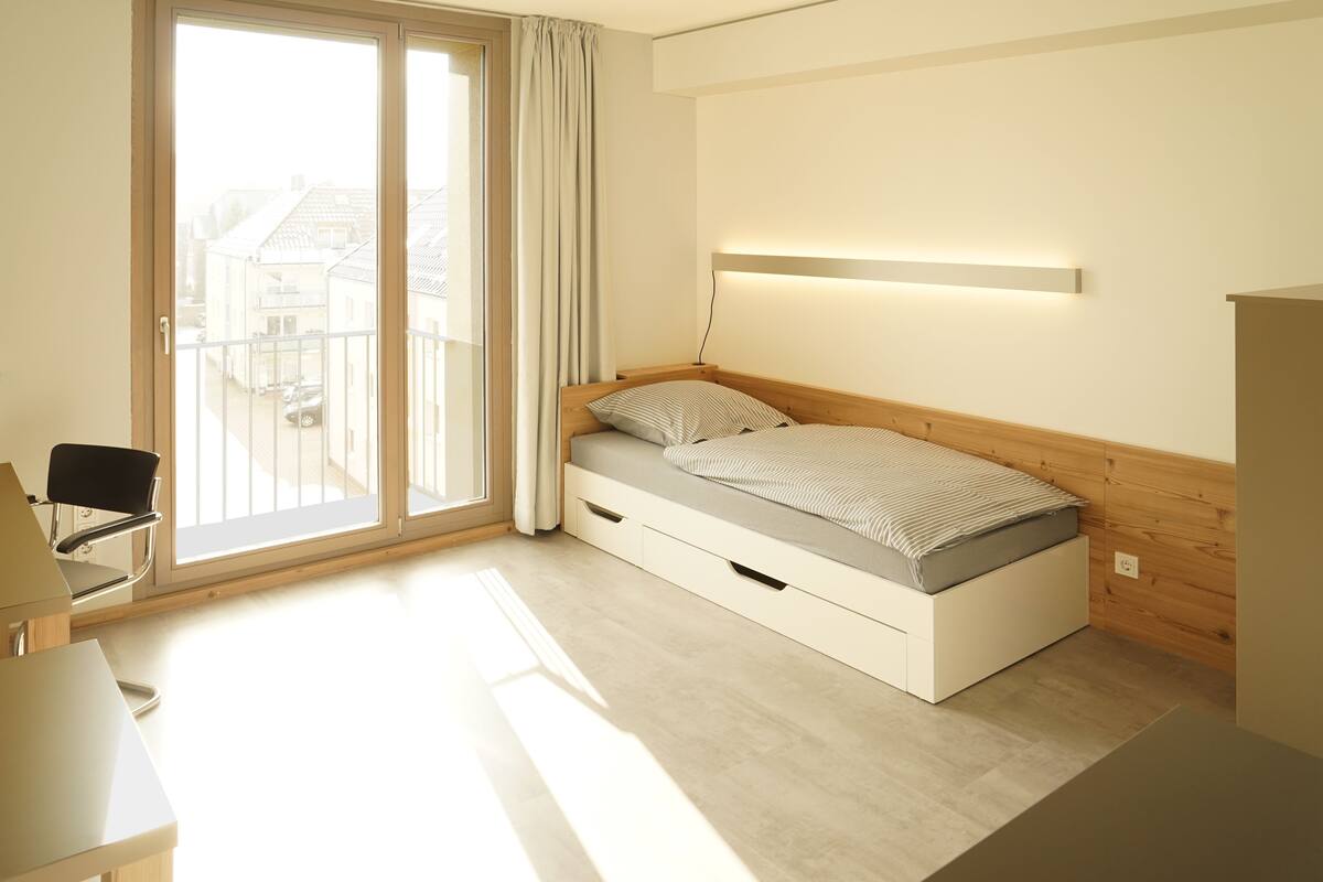Quarto moderno com cama, uma cadeira e uma escrivaninha.