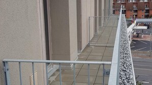 Un bâtiment doté d’un long balcon étroit, agrémenté de rampes en métal et d’un jardon en pierre.