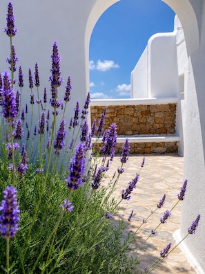 A white building with a stone wall and a clear blue sky. - Eleftheria Hotel (Mykonos)