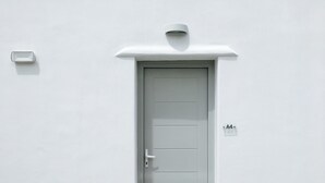 A white door with a handle and a peephole, a small light fixture above it, and a wall-mounted label with the number "A4". - Eleftheria Hotel (Mykonos)