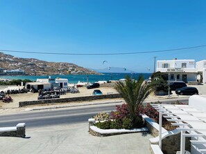 A coastal road with parked vehicles and a bakery. - Eleftheria Hotel (Mykonos)